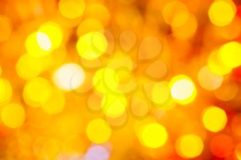abstract blurred background - yellow and red shimmering Christmas lights of electric garlands on Xmas tree
