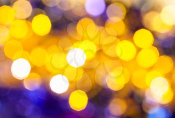 abstract blurred background - dark yellow and violet flickering Christmas lights of electric garlands on Xmas tree