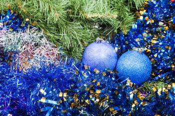 Christmas still life - pair of blue and violet Christmas balls, tinsel on Xmas tree background