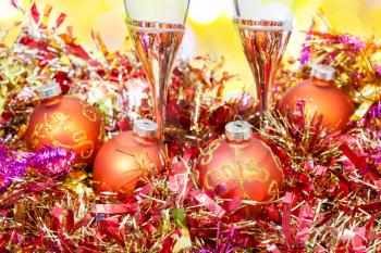 Christmas still life - two glasses of champagne at golden Xmas decorations close up with yellow blurred Christmas lights background
