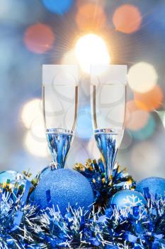 Christmas still life - two glasses of champagne at blue Xmas decorations with pink and blue blurred Christmas lights background