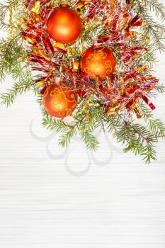 Christmas greeting card - border from three orange Xmas balls and tree branch on blank paper background