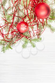 Christmas greeting card - border from two red Xmas balls and tree branch on blank paper background