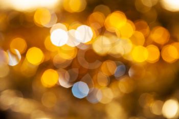 abstract blurred background - yellow and brown shimmering Christmas lights of electric garlands on Xmas tree