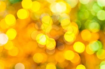 abstract blurred background - yellow and green shimmering Christmas lights of electric garlands on Xmas tree