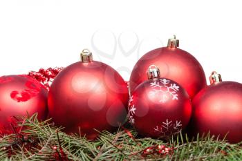 red Christmas balls on green spruce branch isolated on white background