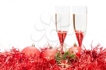two glasses of sparkling wine and angel figure at red Christmas balls and tinsel isolated on white background