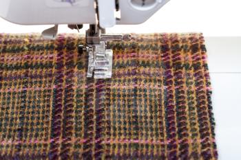 foot of sewing machine on woolen textile close up