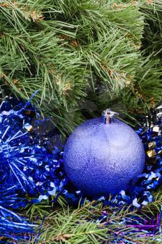 Christmas still life - one violet Christmas ball close up, tinsel on Xmas tree background