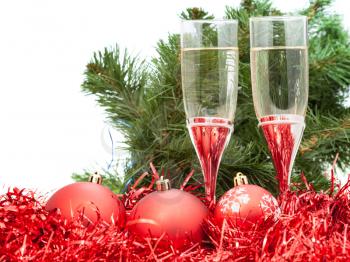 two glasses of champagne at red Christmas decorations with greet branch of Xmas tree on white background