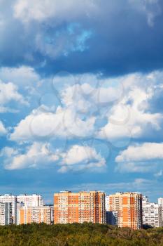 blue and white low clouds over apartment buildings in summer