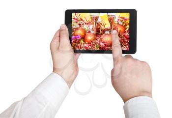 businessman touches tablet pc with Christmas still life on screen isolated on white background