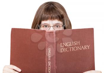 front view of girl with spectacles looks over English Dictionary book isolated on white background