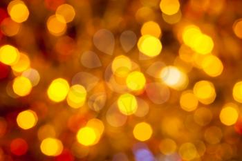 abstract blurred background - dark brown yellow and red shimmering Christmas lights bokeh of electric garlands on Xmas tree