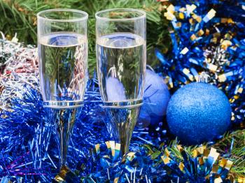Christmas still life - Two glasses of champagne with blue Xmas balls and tinsel and on Christmas tree background