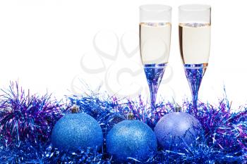 two glasses of champagne at blue and violet Christmas balls and tinsel isolated on white background