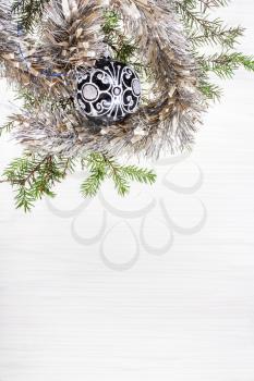 Christmas greeting card - border from one black glass Xmas bauble and tree branch on blank paper background