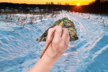 nature concept - seasons and weather changing: hand with paintbrush paints green meadow in sand desert