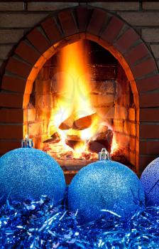 blue Christmas balls and tinsel with open fire in home fireplace