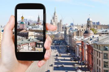 travel concept - tourist photographs picture of Moscow street in historical center on smartphone