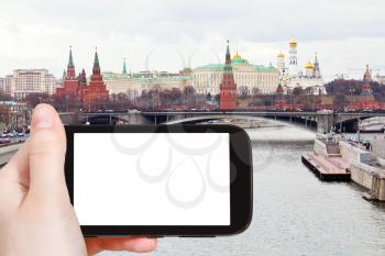 travel concept - hand holds smartphone with cut out screen and Moskva River and Moscow Kremlin on background