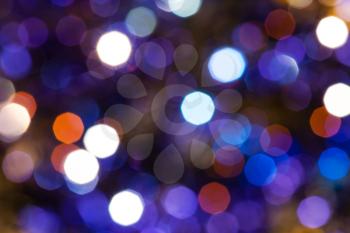 abstract blurred background - dark blue and violet twinkling Christmas lights bokeh of electric garlands on Xmas tree