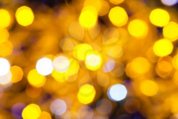 abstract blurred background - dark blue and yellow shimmering Christmas lights bokeh of electric garlands on Xmas tree