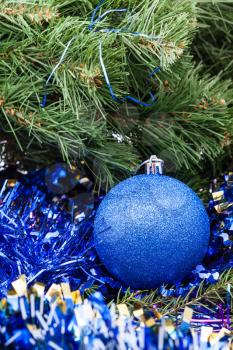 Christmas still life - one blue Christmas ball close up, tinsel on Xmas tree background