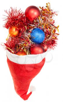 christmas gifts - xmas balls and decorations overflow from red santa hat on white background