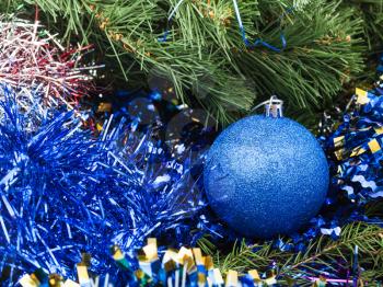Christmas still life - one blue Christmas bauble close up, tinsel on Xmas tree background