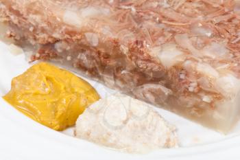 mustard and horseradish - typical seasonings for jellied beef meat on white plate close up