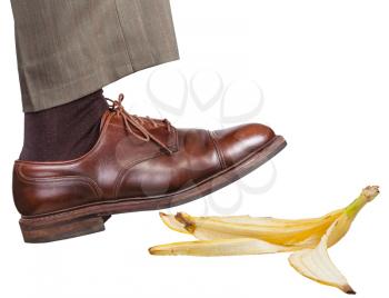 male leg in the right brown shoe slips on a banana peel isolated on white background
