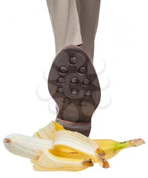 male leg in the left brown shoe stepping on banana peel isolated on white background