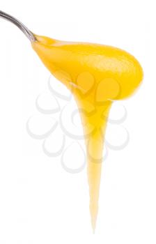 yellow honey flows down from metal spoon close up isolated on white background