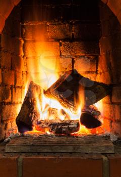 burning firewood in fire-box of fireplace in country cottage