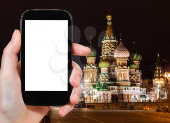 travel concept - tourist photographs Moscow night landscape with Kremlin Pokrovskiy Cathedral on Red Square on smartphone with cut out screen with blank place for advertising, Russia