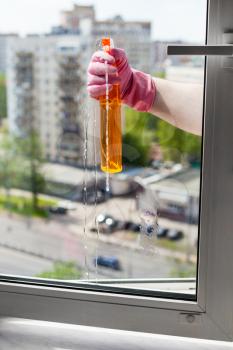 washing home window - washer sprays liquid from spray bottle to window glass in apartment house