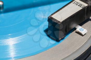 headshell of old turntable on blue flexi disc close up