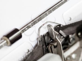 side view of typebar hits ink ribbon in old typewriter close up