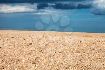Foreground focus - scenery with sand beach and dark blue rain clouds over sea. Coastline of Sea of Azov, Temryuk bay, Golubitskaya resort, Taman peninsula, Kuban, Russia