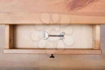 top view of one safe key in open drawer of nightstand