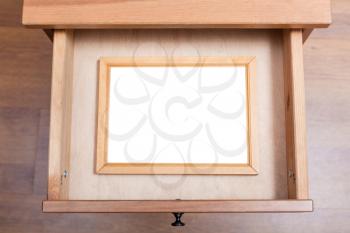 above view of wooden picture frame with cut out canvas in open drawer of nightstand