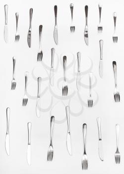 vertical set of table knives and forks on white background