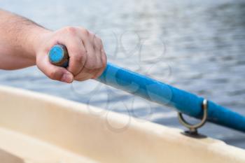 rower's hand holding oar close up while boating
