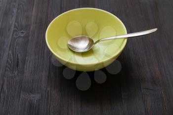 one green bowl with steel spoon on dark brown board