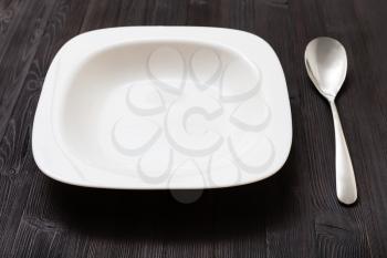 one white bowl with steel on dark brown board