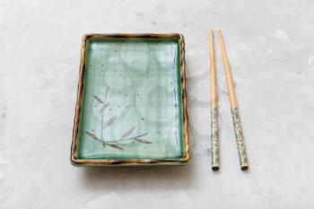 green plate and chopsticks on gray concrete board