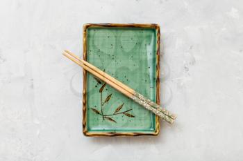 top view of green plate with chopsticks on gray concrete surface