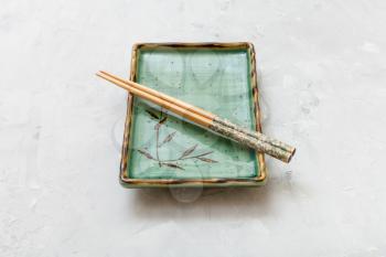 green plate with chopsticks on gray concrete surface