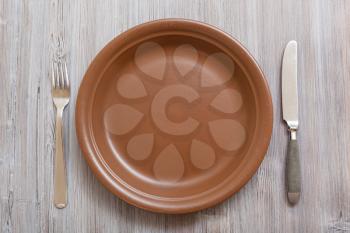 food concept - top view of brown plate, knife, spoon on gray brown table